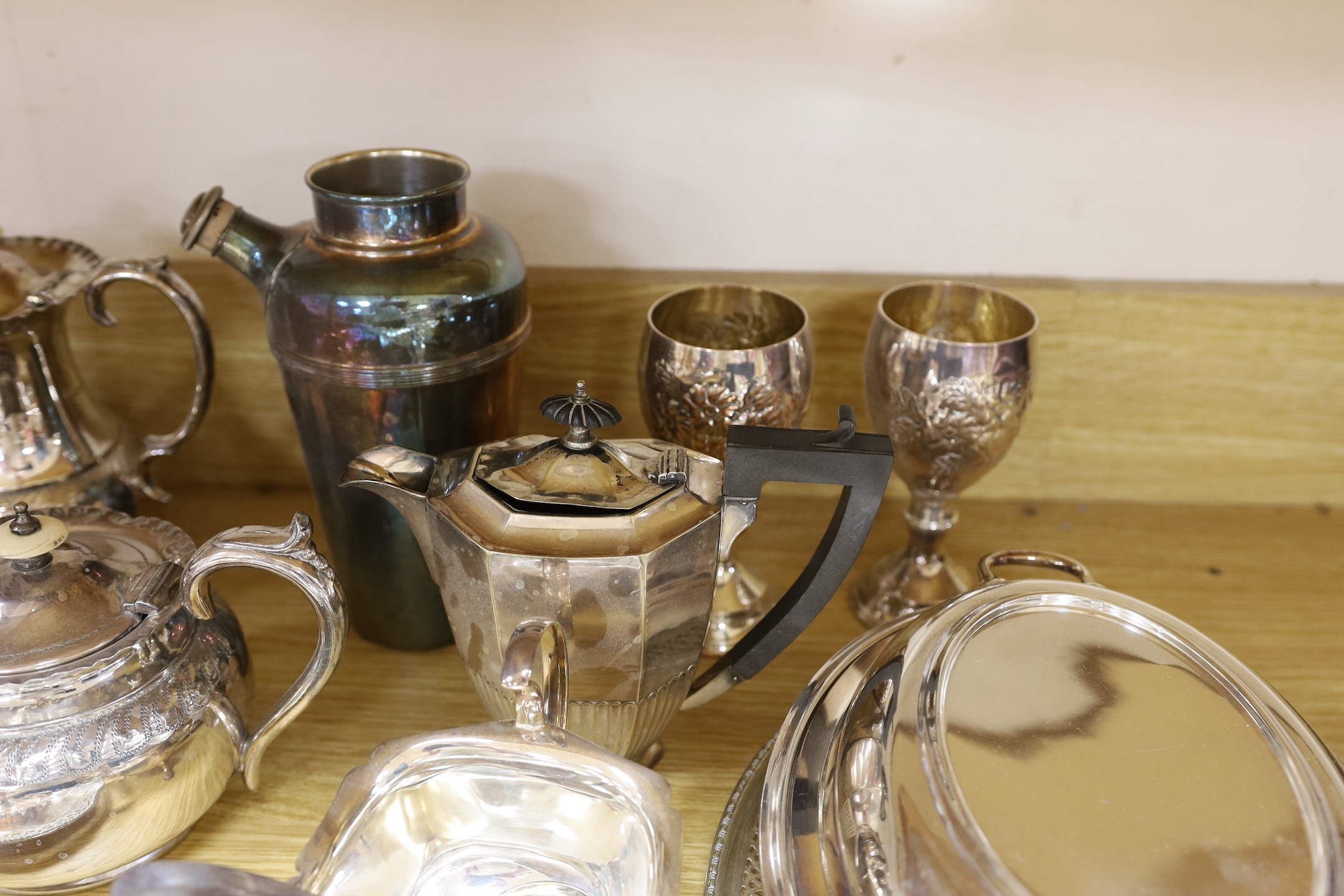 A quantity of assorted plated wares including a chamberstick, a tea set, flatware, a cocktail shaker, a sauceboat, goblets, etc.